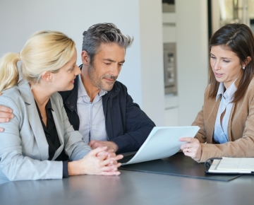 couple receiving advice from woman with paper