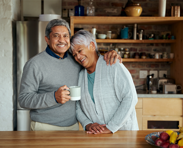 couple embracing from the side in the kitchen with cup of coffee