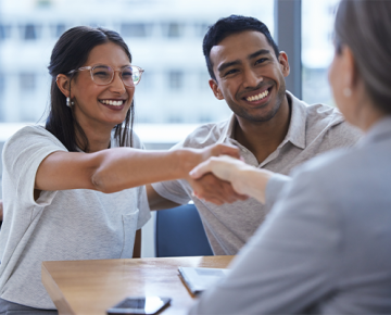 couple shaking the hand of a woman they are meeting with