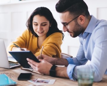 couple taking notes on tablet and laptop