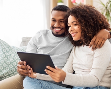 couple on couch looking at tablet