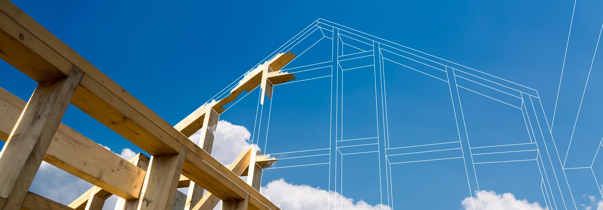 Frame of a house with outline of blueprints against a blue sky