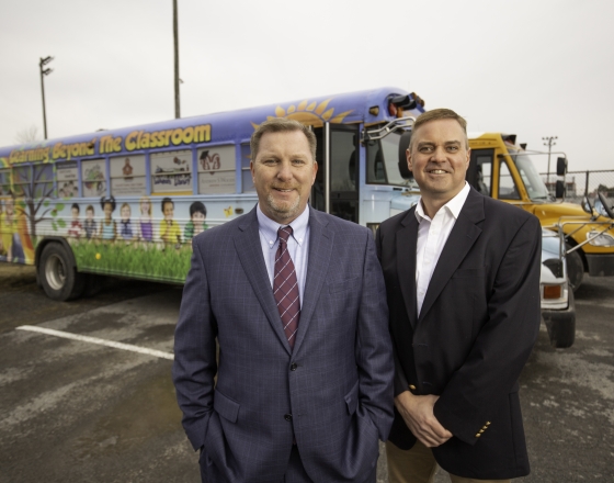 Two People Standing In Front of Bus